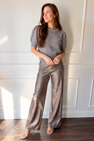 Model wearing the Jeiel pewter satin wide-leg pants with a grey sweater and metallic heels.
